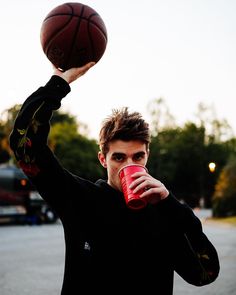 a man holding a basketball and drinking from a red cup