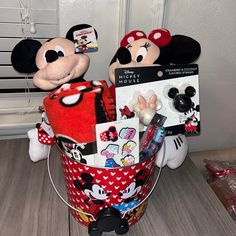 mickey and minnie mouses are sitting in a basket with other items on the table