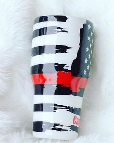 a red, white and blue coffee cup sitting on top of a fluffy white blanket