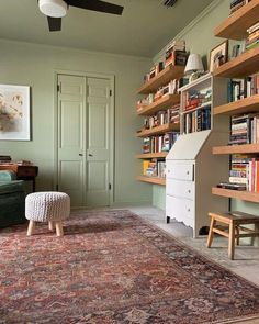 a living room filled with furniture and bookshelves next to a green couch in front of a doorway