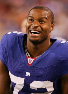 a close up of a person wearing a football uniform and smiling at the camera with an audience in the background