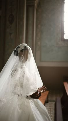 a woman in a white wedding dress and veil sitting at a table with a piano