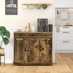 a kitchen with white cabinets and wooden floors, coffee maker on the counter next to a potted plant