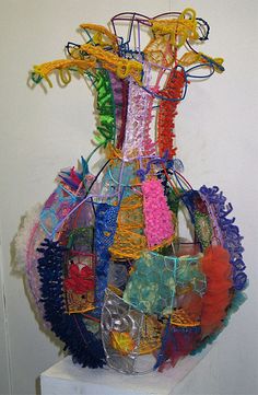 there is a sculpture made out of many different pieces of cloth and thread on top of a white pedestal