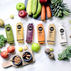 various fruits and vegetables on a table with juices, nuts, avocados