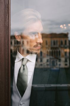 a man in a suit and tie looking out the window