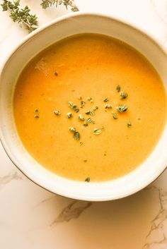 a white bowl filled with soup sitting on top of a counter next to a spoon