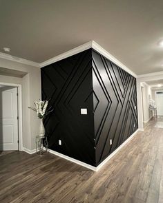 an empty room with wood flooring and black wall covering the entire area in this house