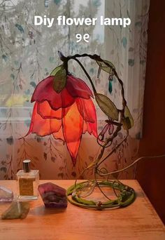 a lamp that is sitting on top of a table next to some rocks and flowers