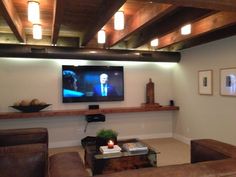 a flat screen tv mounted to the side of a wall in a living room with leather furniture