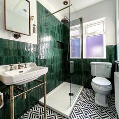 a bathroom with black and white tiles on the floor, green walls, and two sinks