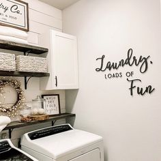 laundry loads of fun sign above washer and dryer in small room with white cabinets