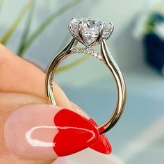 a close up of a person's hand holding a ring with a heart on it