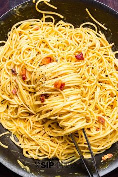 spaghetti with bacon and parmesan cheese in a skillet, ready to be eaten