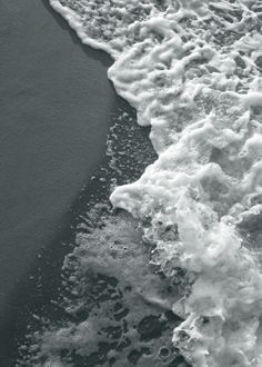 the water is foamy on the beach and it looks like waves are coming in