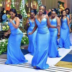 a group of women in blue dresses walking down the aisle with one woman holding her hand out