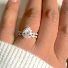 a woman's hand with a diamond ring on top of her finger and a white sweater