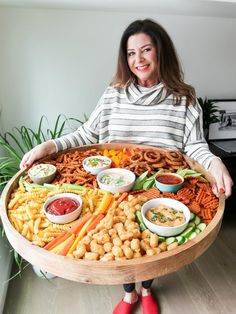 a woman is holding a large platter full of different types of food and dipping sauces