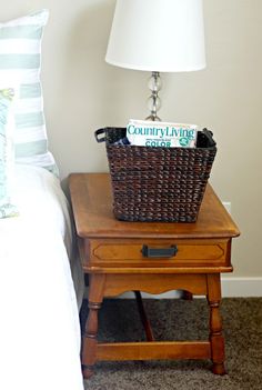 a basket sitting on top of a wooden table next to a night stand with a lamp