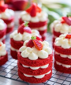 several red velvet cakes with white frosting and strawberries on top are sitting on a cooling rack