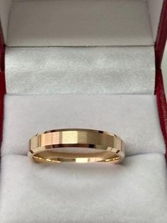 a gold wedding band in a red box