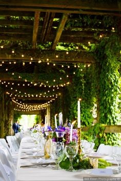 the table is set with white linens and purple flowers