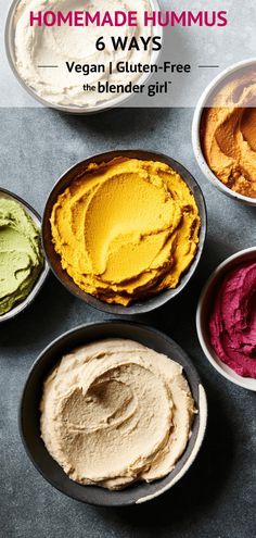 four bowls filled with different colored hummus on top of a gray table next to each other