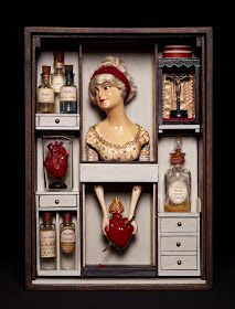 a doll in a wooden box with many bottles and jars on it's shelves