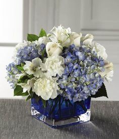 a blue vase filled with white flowers on top of a table