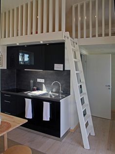 a kitchen with a ladder to the loft above it and a sink in the middle