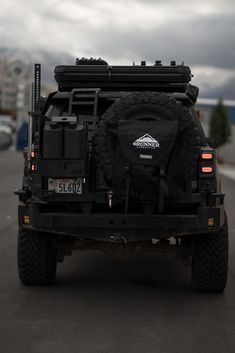 the back end of a black truck on a road