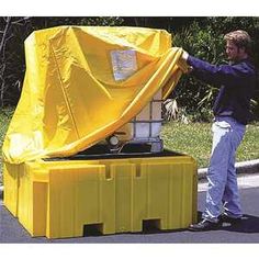 a man unloading a yellow plastic box on the side of the road with trees in the background