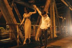 a man and woman dancing on a bridge at night