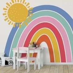 a child's room with a rainbow wall decal on the wall and a table in front of it