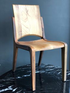 a wooden chair sitting on top of a black marble floor next to a gray wall