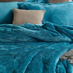 a bed covered in blue blankets and pillows