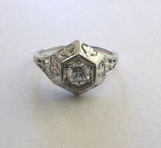 This beautiful antique engagement ring is Art Nouveau style integrating graceful organic forms with floral and open filigree detail.  A beautiful Old European Cut diamond is set inside a hexagonal illusion setting making it look larger. It has a beautifully designed and substantial art deco period setting. The stone is bright and white with beautiful sparkle and a very small open culet. It is approximately 36 points, slightly over 1/3 carat. Please view photos and read entire description and pol Victorian Platinum Filigree Wedding Ring, Vintage Filigree Diamond Ring For Wedding, Antique White Wedding Dress With Intricate Design, Art Deco Filigree Ring For Promise, Ornate Diamond Ring With Intricate Design For Anniversary, White Gold Filigree Ring With Intricate Design For Promise, Art Deco Filigree Ring With Center Stone For Wedding, Art Deco Filigree Ring For Wedding With Center Stone, Ornate Filigree Wedding Ring With Diamond Cut