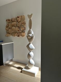 a white sculpture sitting on top of a wooden table next to a wall mounted art piece