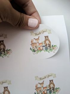 a hand holding a sticker that says thank you with woodland animals and leaves on it