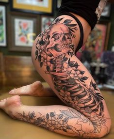 a woman's leg with a skeleton and flowers tattoo design on the lower half