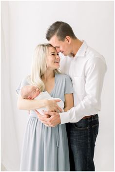 a man and woman holding a baby in their arms