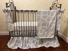 a baby crib with blue and white bedding next to a brown wooden floor