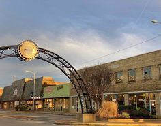 an arch in the middle of a street with shops on both sides and buildings to the side