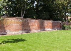 a brick wall in the middle of a grassy area