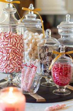 candy and candies in glass containers on a table with candles, napkins and other items