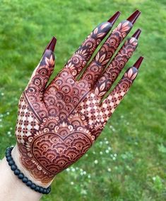 a woman's hand with hennap on it in front of some grass