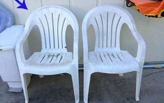 two white plastic chairs sitting next to each other in front of a wall with an orange arrow on it