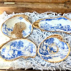 four blue and white plates in a box with lace on the bottom, one has a gold ring