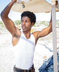 a young man is holding his surfboard over his head and posing for the camera