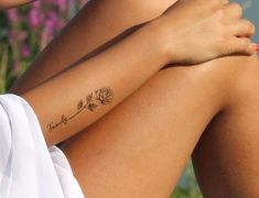 a woman with a tattoo on her arm is sitting in front of some purple flowers